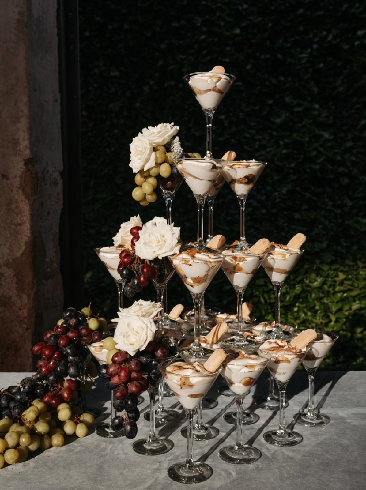 Tiered dessert display with grapes, white roses, and martini-glass tiramisu cups