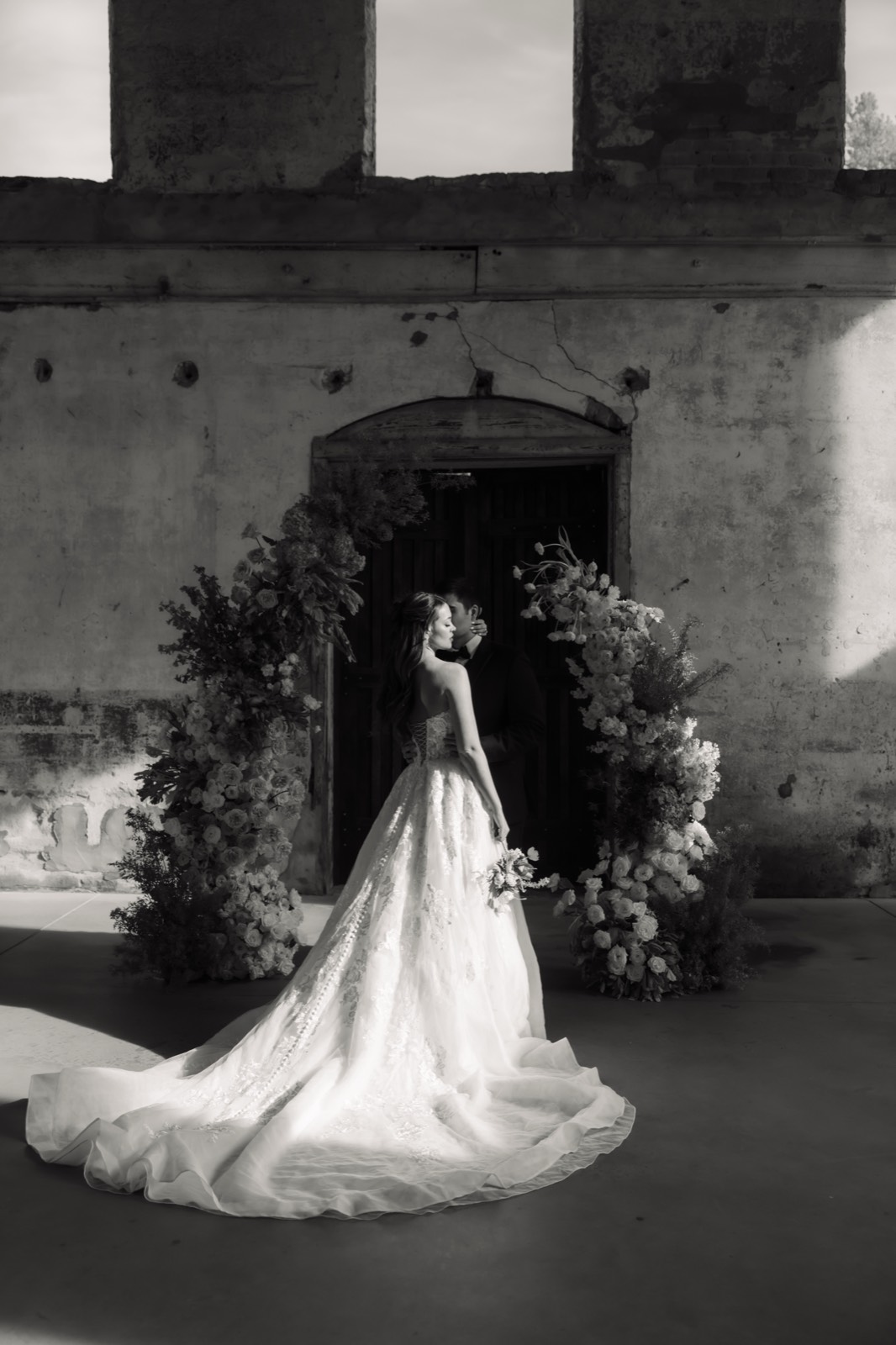 Black and white bridal portrait in front of a floral arch