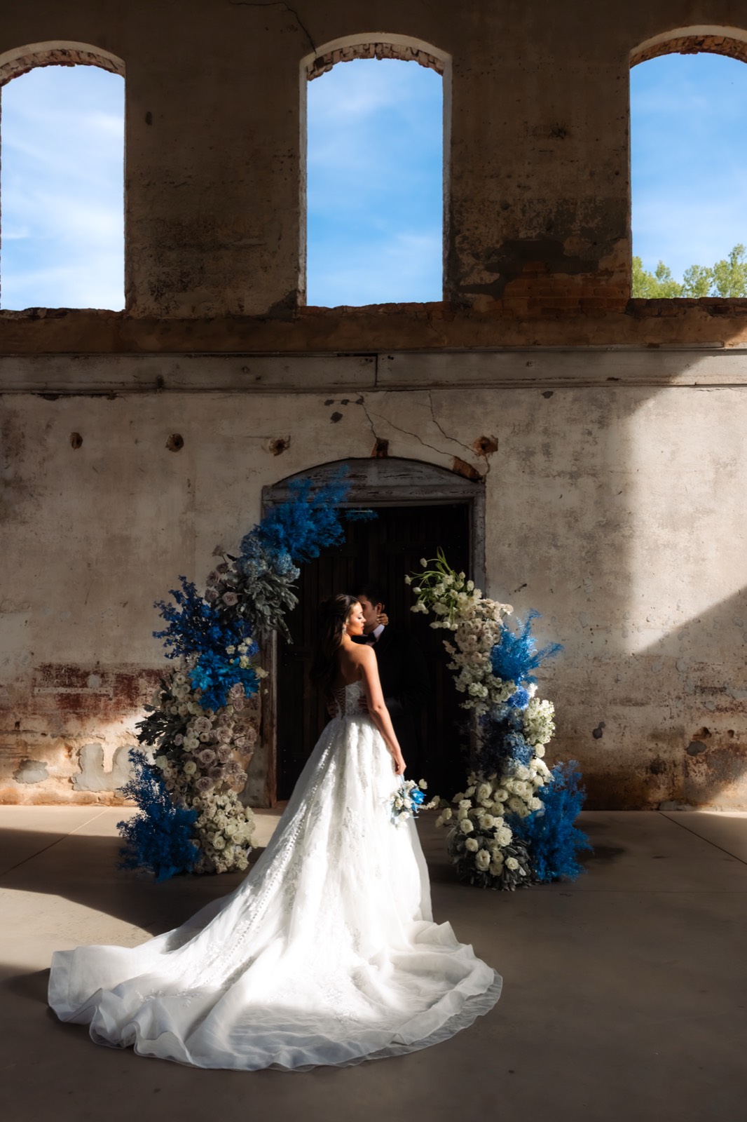 Bride and groom portrait framed by blue and white floral installations