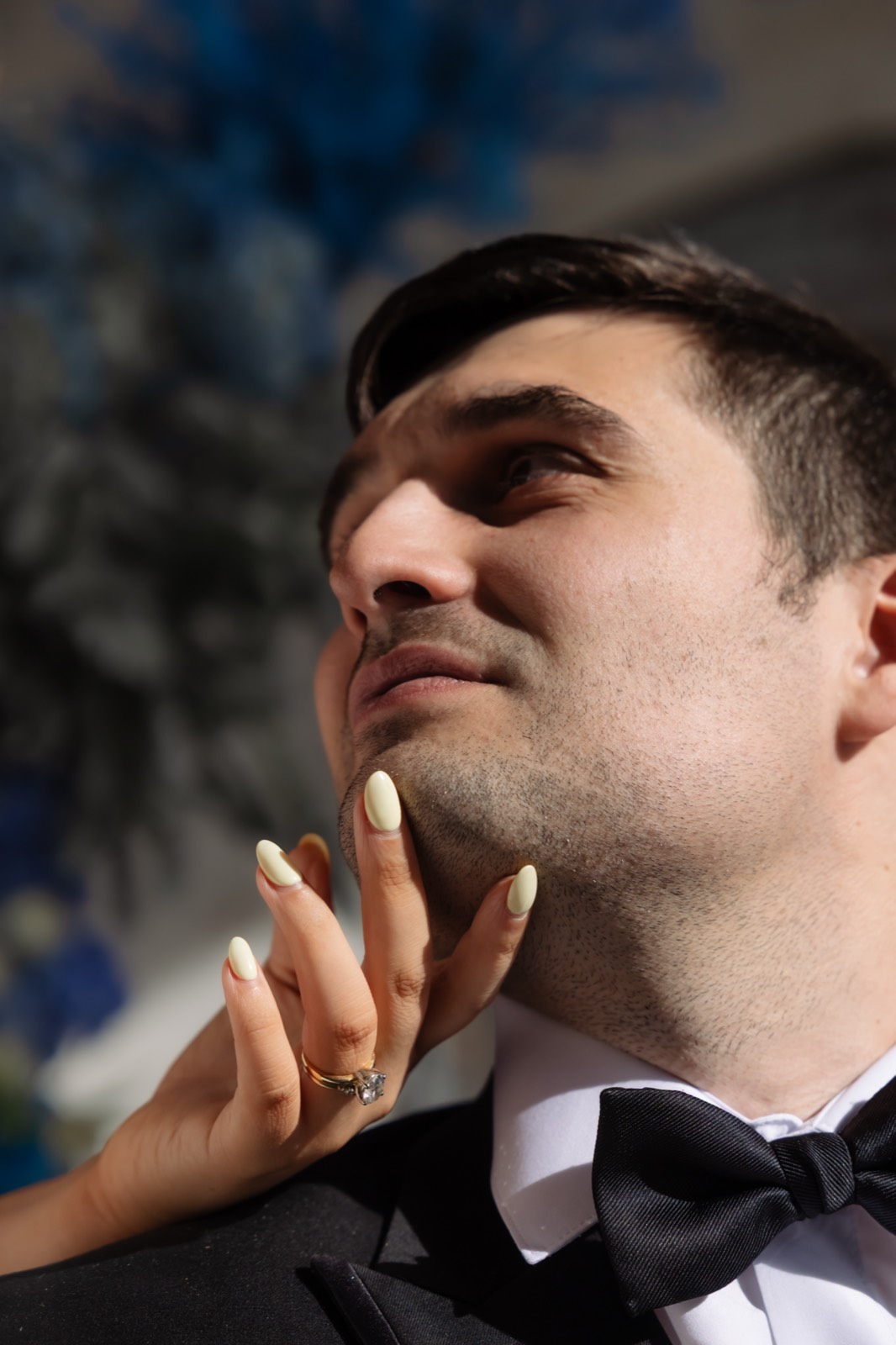 Close-up groom portrait with bride hand and ring detail