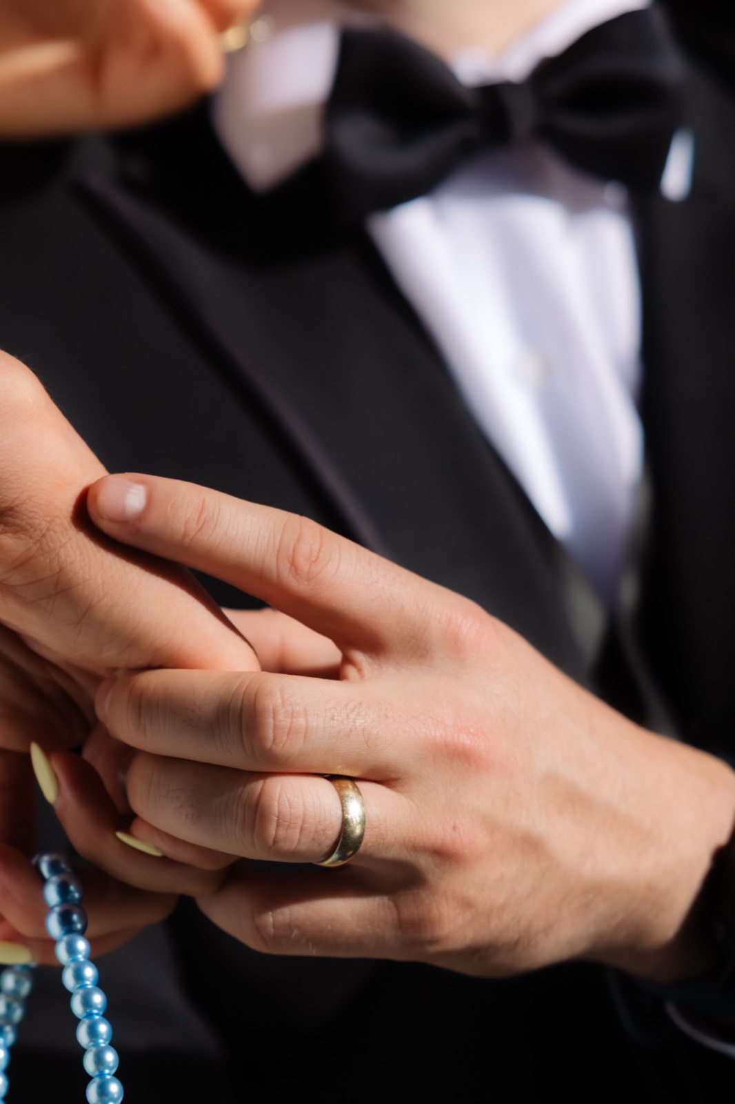 Close-up of couple hands with wedding band and blue pearl detail